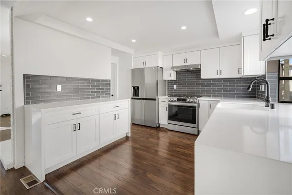a kitchen with stainless steel appliances kitchen island granite countertop a stove a sink and a refrigerator