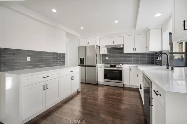a kitchen with stainless steel appliances white cabinets a sink a stove a refrigerator and white cabinets