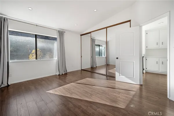 a view of empty room with wooden floor and mirror