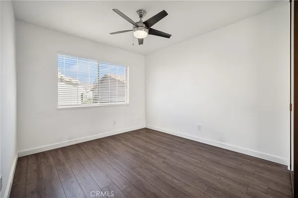 an empty room with wooden floor ceiling fan and windows