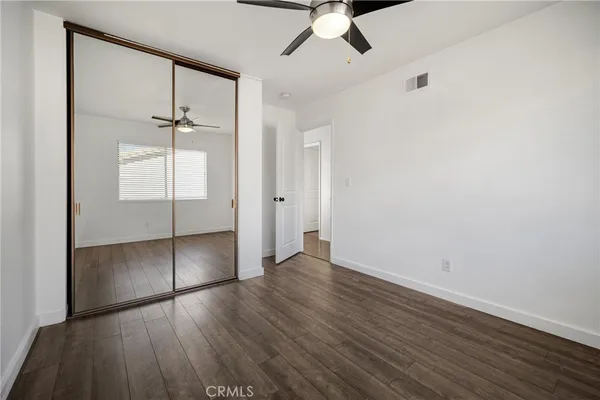 an empty room with wooden floor fan and windows