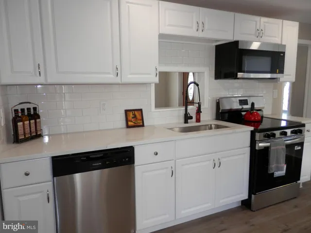 a kitchen with stainless steel appliances a sink a stove and cabinets