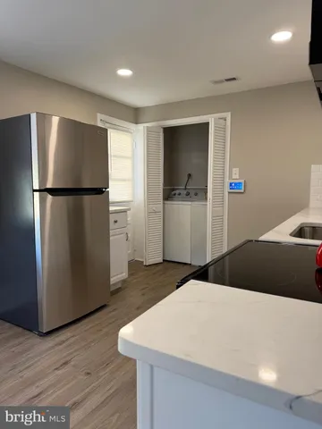 a kitchen with a refrigerator and wooden floor