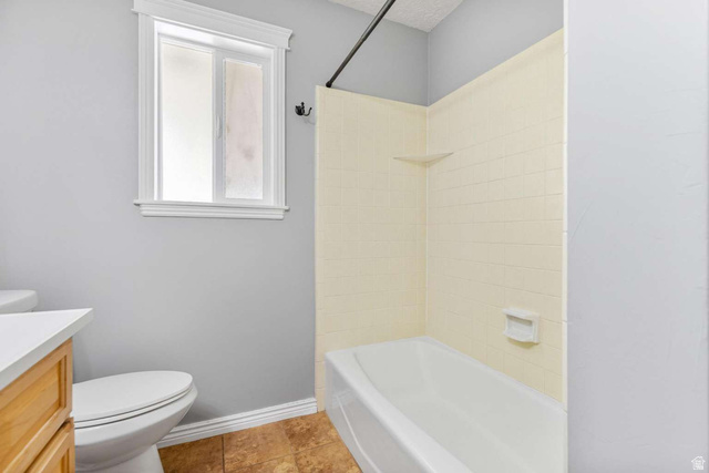 415 East 1150th Street North Logan, UT 84341 - Photo 16 of 38 Bathroom featuring a white bathtub with light-colored tile surround, a built-in shelf, and a frosted window with white trim