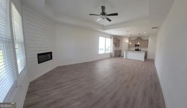 a view of a big room with wooden floor a ceiling fan and windows