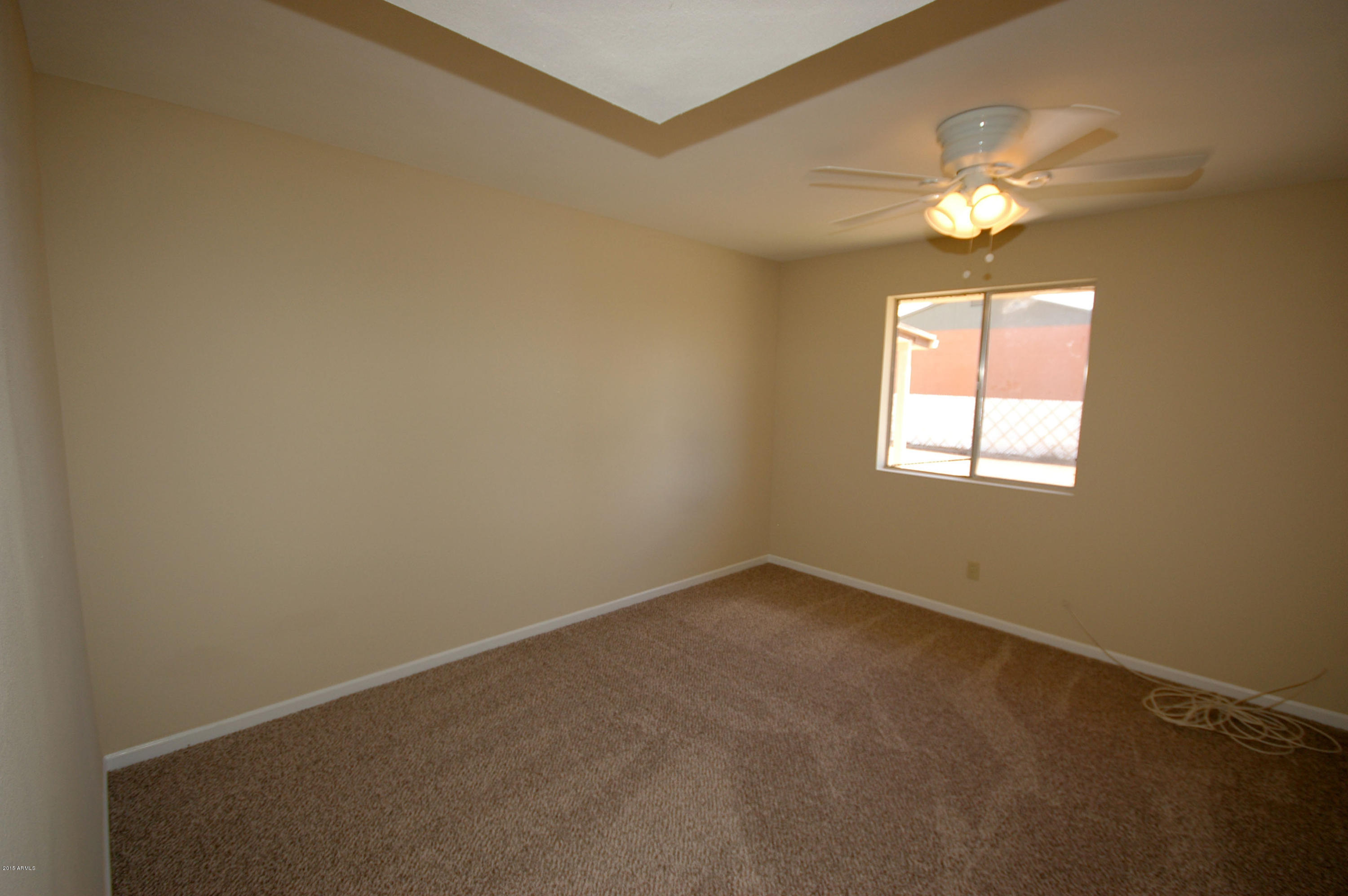 3151 West Redfield Road Phoenix, AZ 85053 - Photo 10 of 15 an empty room with a chandelier fan and windows