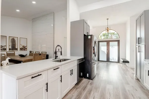 a kitchen with counter top space a sink wooden floor and window