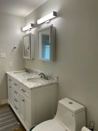 a bathroom with a granite countertop toilet a sink and a mirror