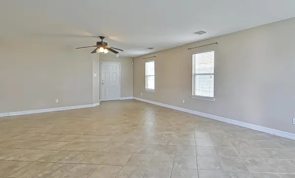 an empty room with windows and chandelier fan
