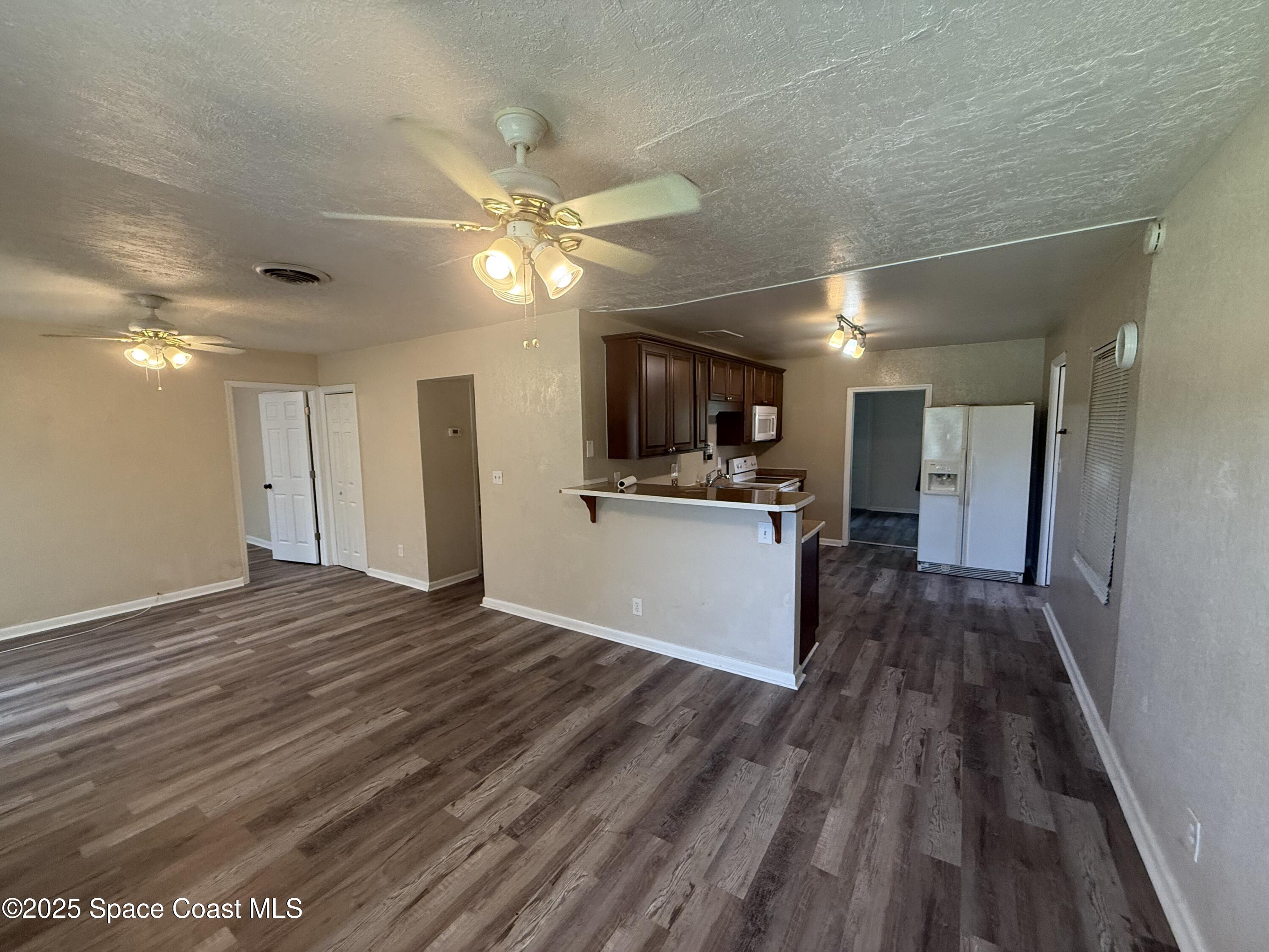 325 Patrick Circle Melbourne, FL 32901 - Photo 2 of 15 a view of a kitchen with a sink a refrigerator a ceiling fan and wooden floor