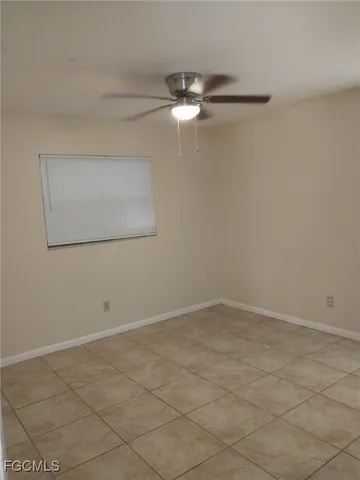 an empty room with a chandelier fan and windows