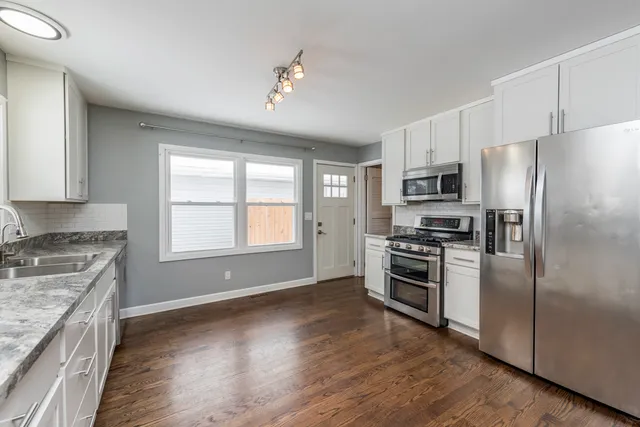 a kitchen with a refrigerator stove and wooden floor