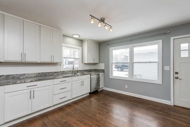 a large kitchen with granite countertop a large window and white appliances