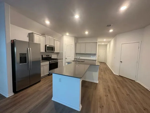 a large kitchen with stainless steel appliances refrigerator a stove and wooden floor