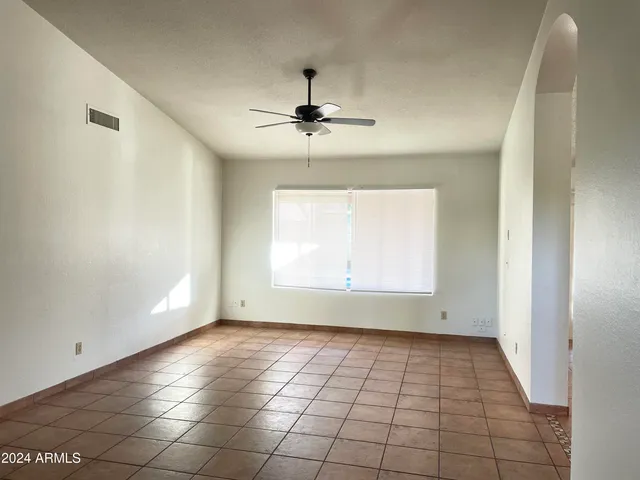an empty room with windows and fan