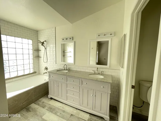 a bathroom with a double vanity sink bathtub and next to a window