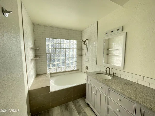 a bathroom with a granite countertop sink a mirror and a bathtub