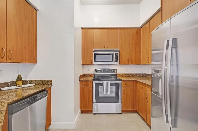 a kitchen with stainless steel appliances granite countertop a refrigerator and a stove top oven