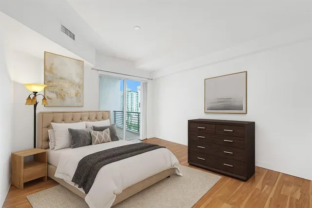 a bedroom with a bed a painting on the wall and a dresser