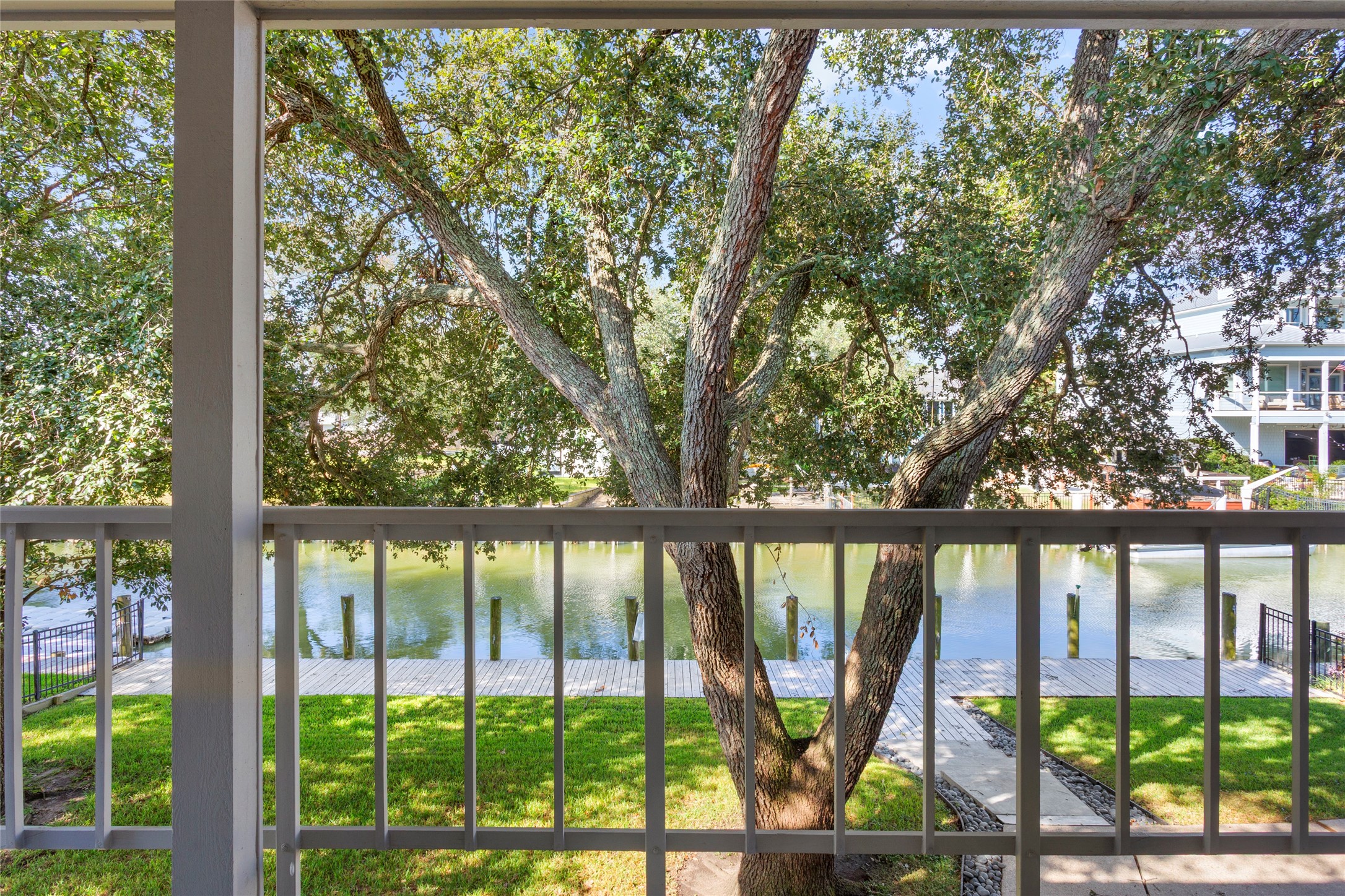 67 Harbor Lane Kemah, TX 77565 - Photo 24 of 47 Incredible views from the balcony overlooking a lush tree, a calm waterfront, and a walkway leading to the bulkhead and water's edge. Ideal for those who appreciate water, nature, and tranquility.