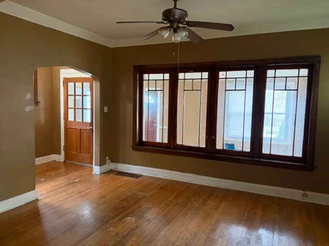 a view of an empty room with wooden floor and a window