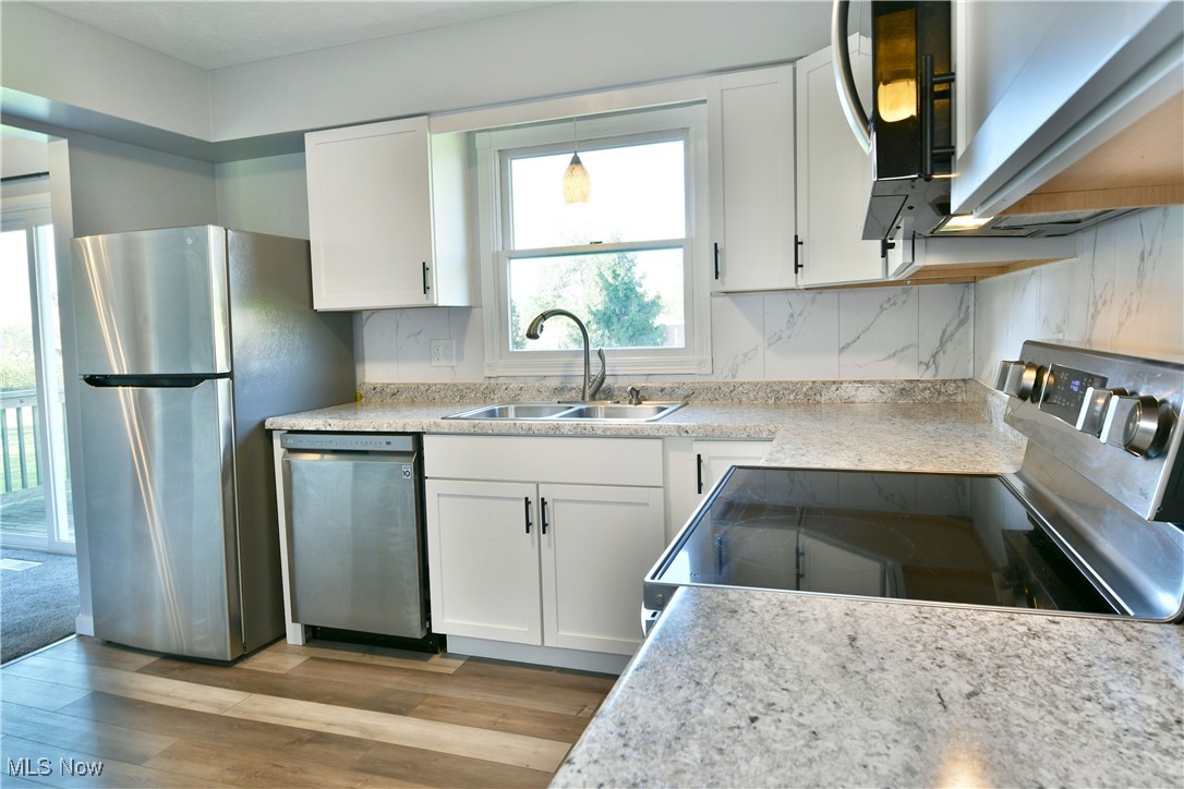 4461 Ridge Road Cortland, OH 44410 - Photo 19 of 47 Kitchen with white cabinetry, sink, stainless steel appliances, and light hardwood / wood-style flooring