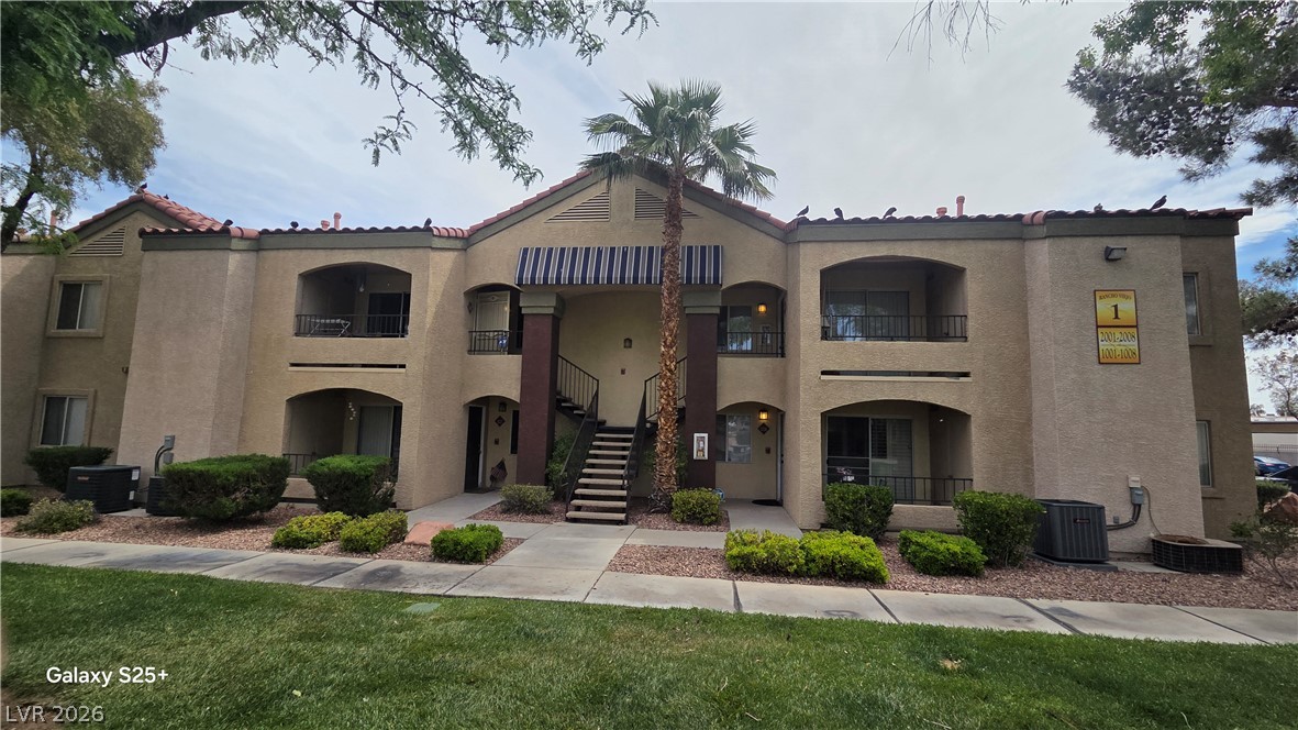 7885 West Flamingo Road, Unit 1008 Las Vegas, NV 89147 - Photo 21 of 29 A welcoming apartment building with balconies and a central stairway, set amidst lush landscaping.