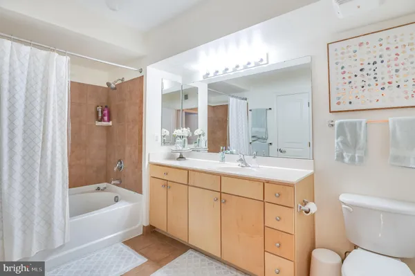 a bathroom with a granite countertop sink a toilet a mirror a vanity a bathtub and shower