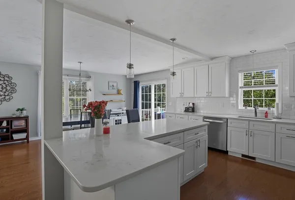 a large white kitchen with granite countertop a stove a sink a dining table and chairs