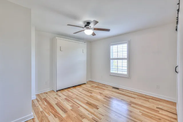 a view of empty room with wooden floor and fan