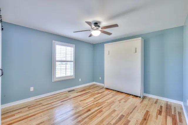 a view of empty room with wooden floor and fan