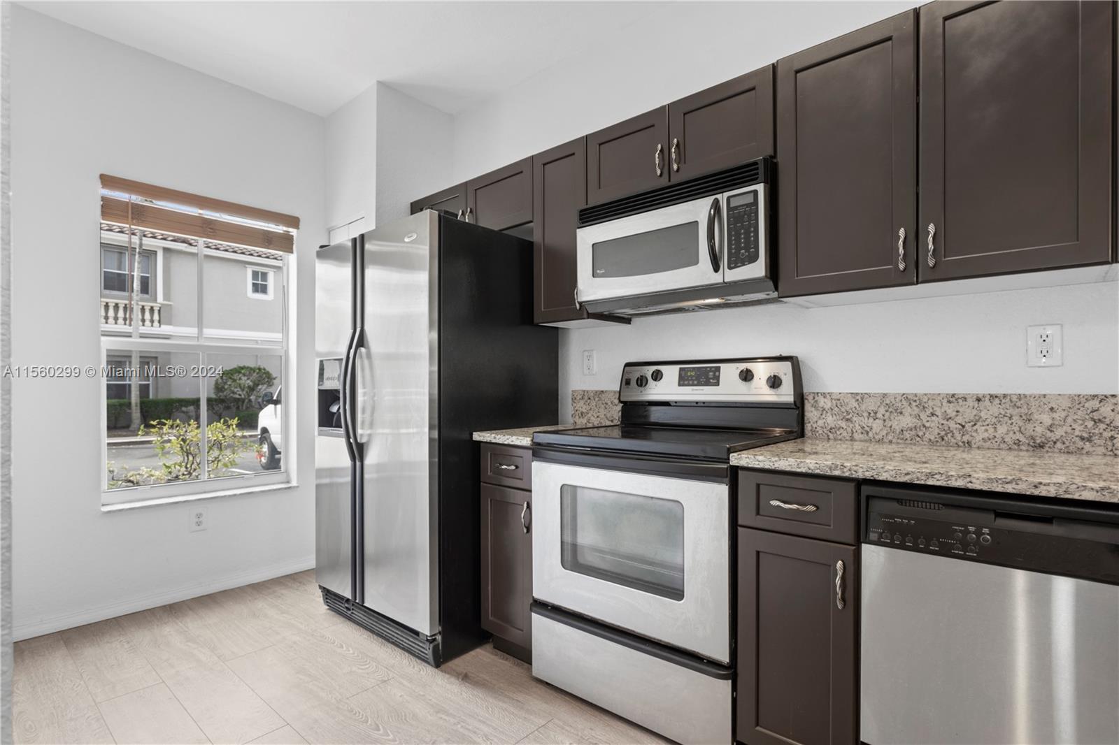 14033 Southwest 49th Street, Unit 6 Miramar, FL 33027 - Photo 3 of 25 a kitchen with stainless steel appliances granite countertop a stove microwave and refrigerator