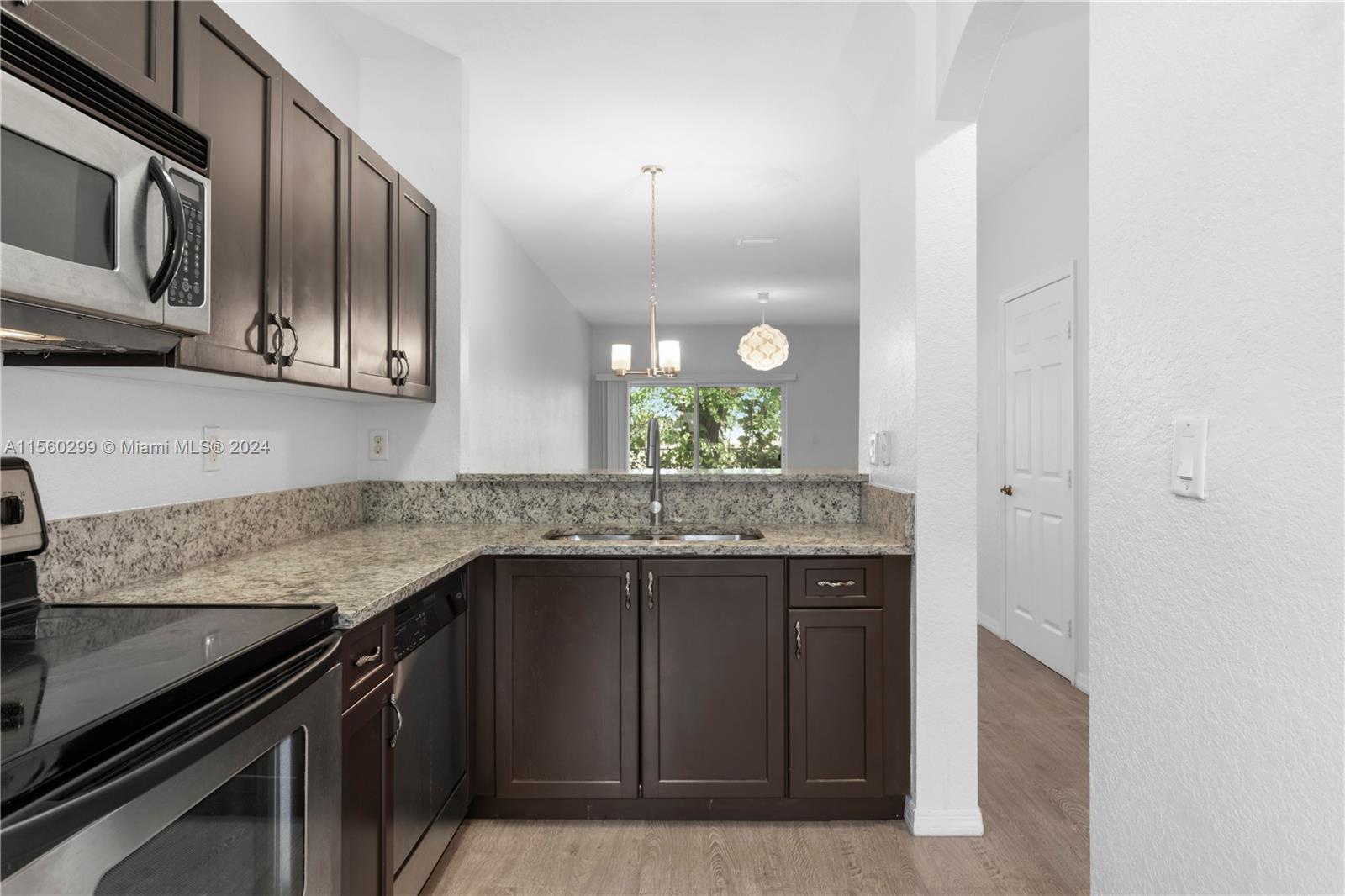 14033 Southwest 49th Street, Unit 6 Miramar, FL 33027 - Photo 5 of 25 a kitchen with granite countertop stainless steel appliances and wooden cabinets