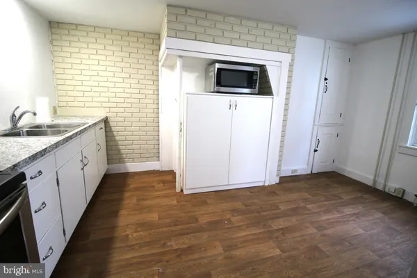 a view of a kitchen with a sink and dishwasher with wooden floor