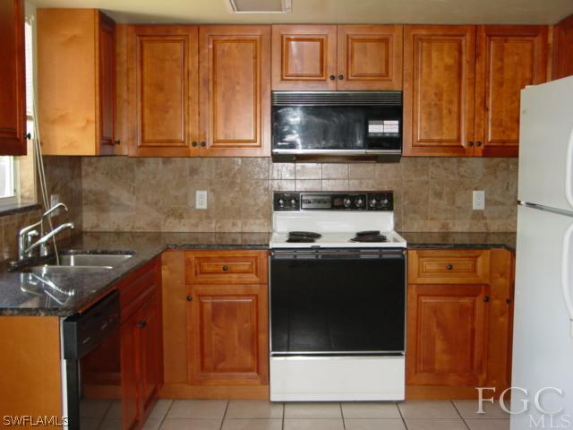 9099 Bryant Road Fort Myers, FL 33967 - Photo 4 of 8 a kitchen with stainless steel appliances granite countertop a stove microwave and sink