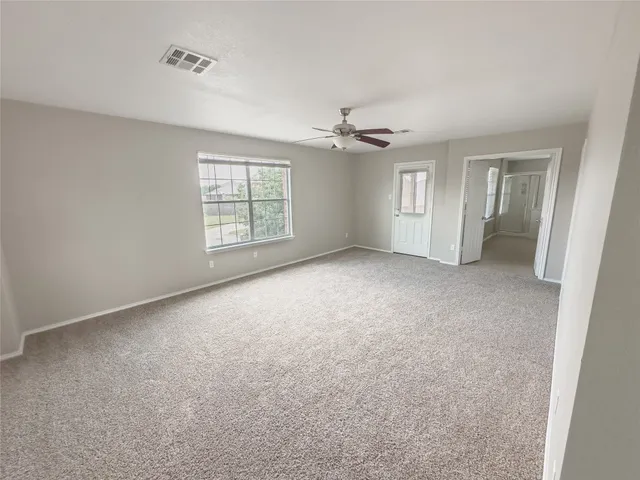 en empty room with windows and ceiling fan