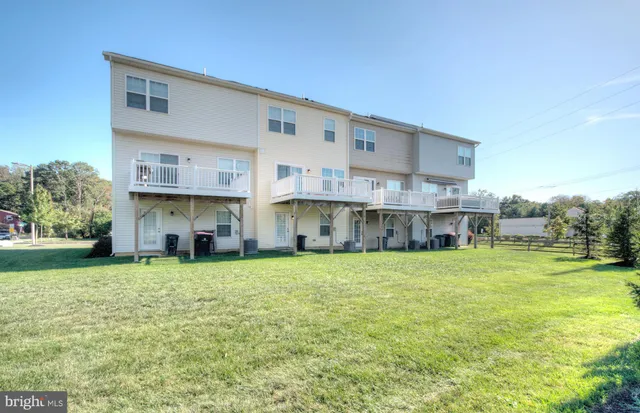 a view of a big yard next to a yard with plants and large trees