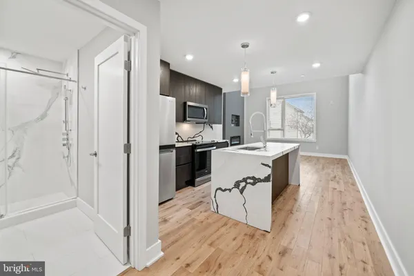 a living room with stainless steel appliances kitchen island granite countertop a refrigerator and a sink