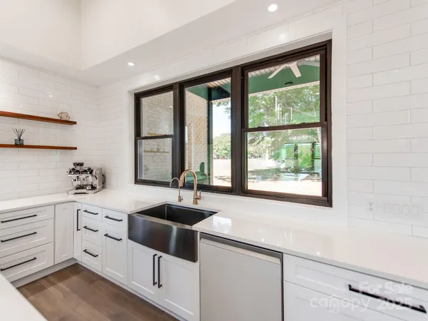 a kitchen with white cabinets and a large window