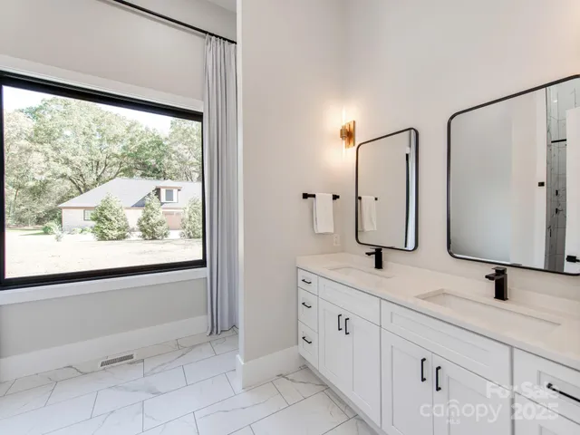 a bathroom with a double vanity sink and mirror with window
