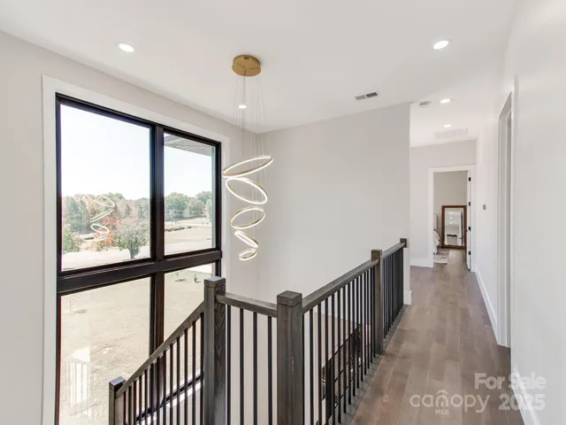 a view of a hallway with wooden floor and windows