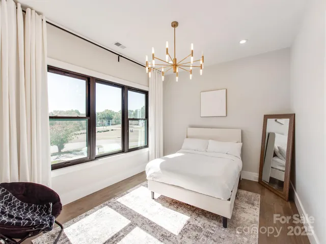 a spacious bedroom with a bed chandelier and a window