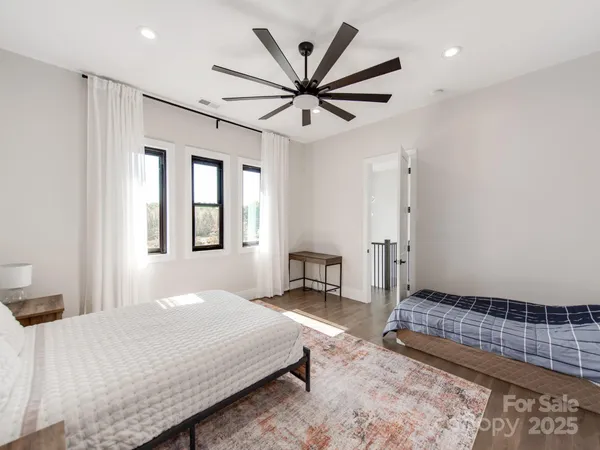 a spacious bedroom with a bed a chandelier and a rug