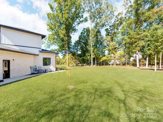 a backyard of a house with large trees and plants