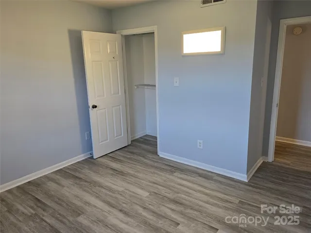 a view of an empty room with wooden floor and closet