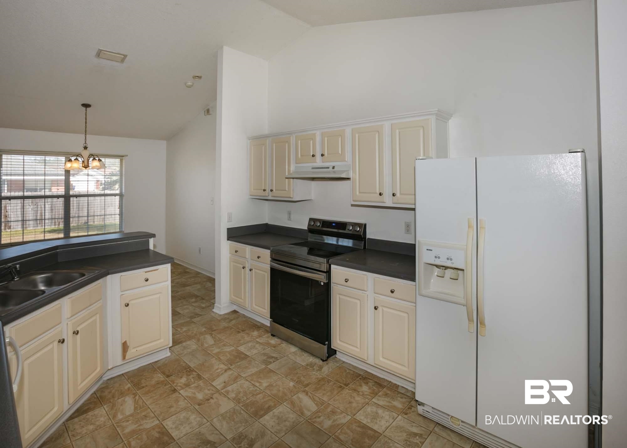 2530 Ashburn Lane Foley, AL 36535 - Photo 9 of 46 Kitchen featuring electric range, white fridge with ice dispenser, hanging light fixtures, a notable chandelier, and vaulted ceiling