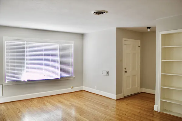 a view of an empty room with wooden floor and a window