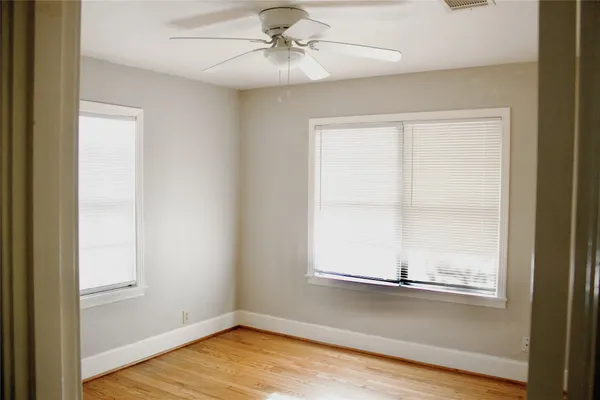 an empty room with wooden floor closet and windows