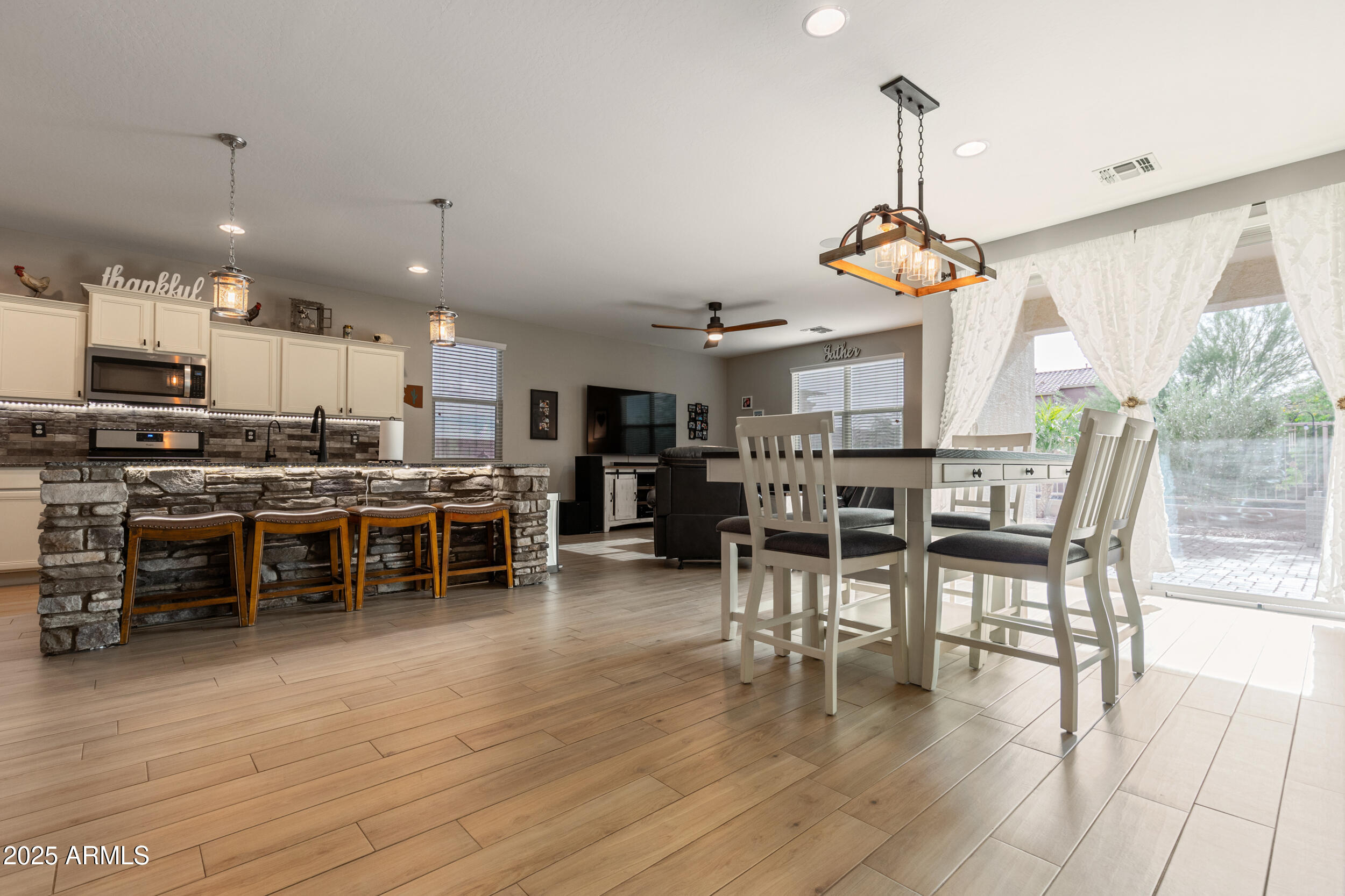37104 Big Bend Road San Tan Valley, AZ 85140 - Photo 7 of 26 a view of a kitchen with dining table chairs wooden floor and appliances