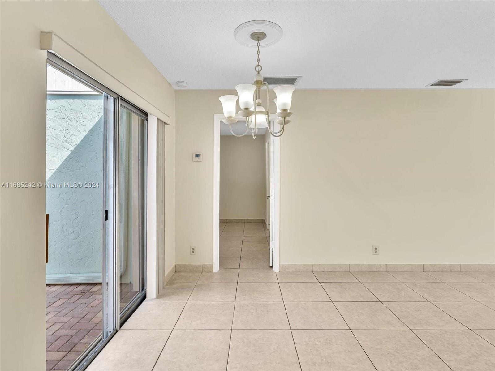 9185 Southwest 5th Street, Unit B Boca Raton, FL 33428 - Photo 15 of 38 a view of a hallway with chandelier and glass door